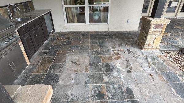 Slate tile patio with outdoor kitchen before soft washing by Stonevale Exterior Co. showing dirt and buildup