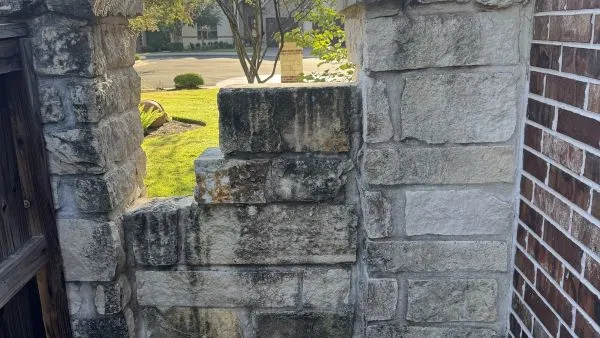 Stone alley wall before soft washing by Stonevale Exterior Co. showing dark algae and mold buildup