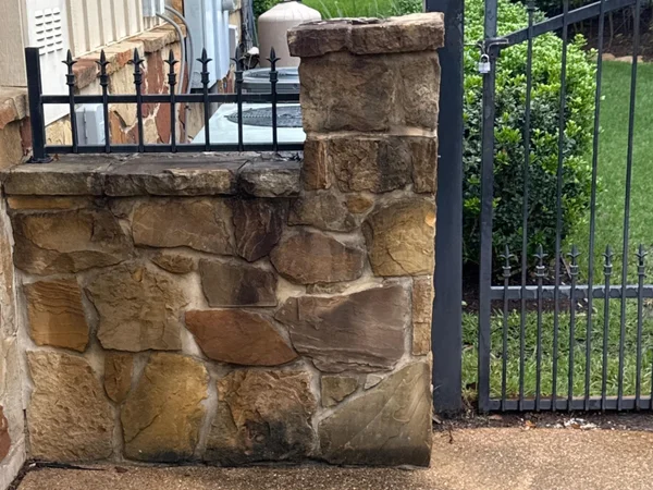 Flagstone driveway divider and pillar before cleaning by Stonevale Exterior Co. showing dark weathered stone