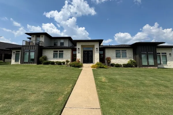 Beautiful stone and dark panel residential home with manicured lawn in Brazos Valley, Texas
